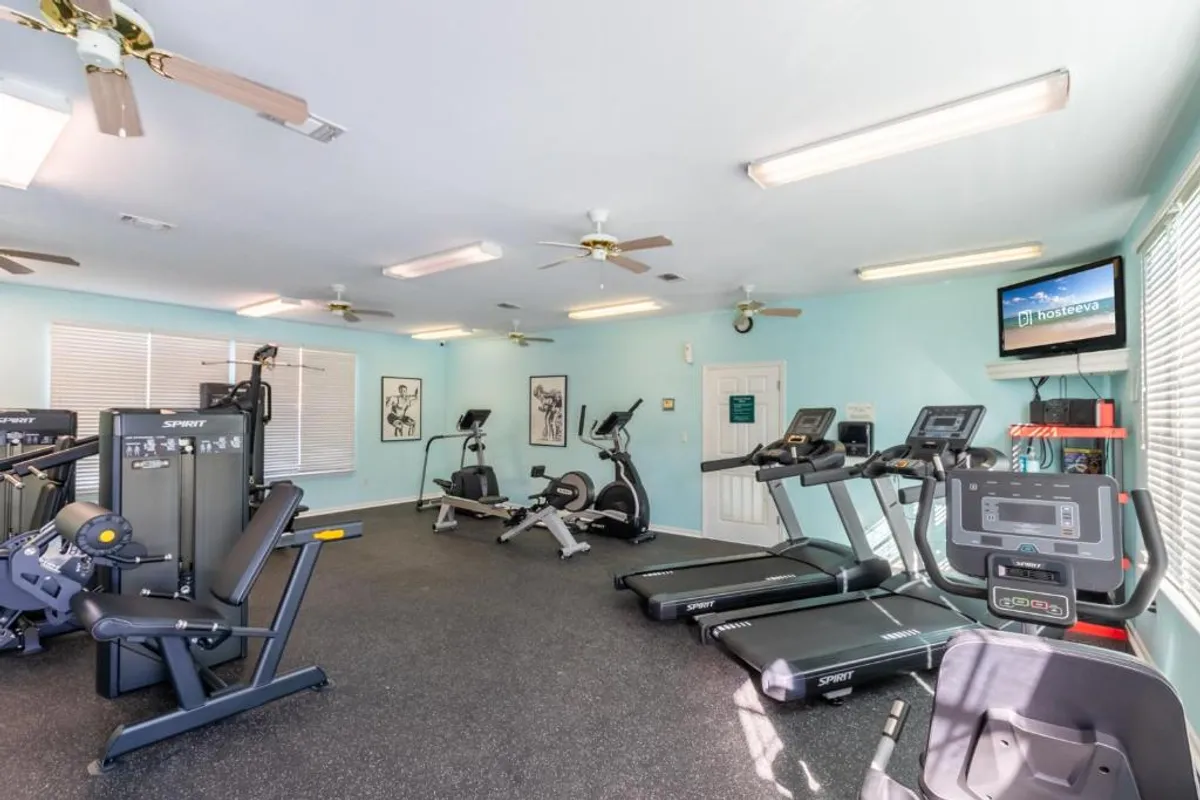 A modern, well-equipped fitness center with treadmills, exercise bikes, weight machines, and a TV screen. The space is bright and motivational, providing a dedicated area for personal fitness routines or community group workouts.