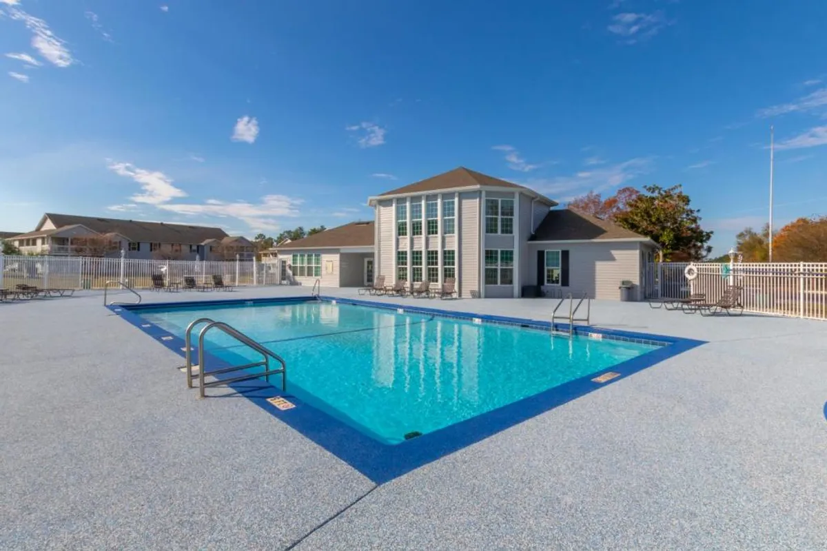 This image captures the sparkling swimming pool at the Colony Club community, surrounded by lounge chairs and the clubhouse in the background. The setting exudes a cheerful, family-friendly vibe, perfect for post-tournament relaxation or group gatherings.
