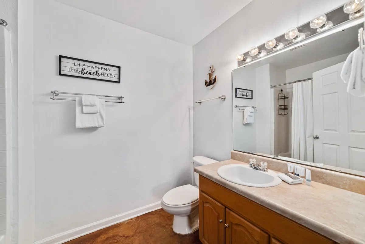 A sparkling bathroom with a well-lit mirror, organized vanity, framed wall art, and a neatly arranged towel rack. The surfaces gleam and the ambiance is calm and refreshing, evoking daily routines in an immaculate setting.