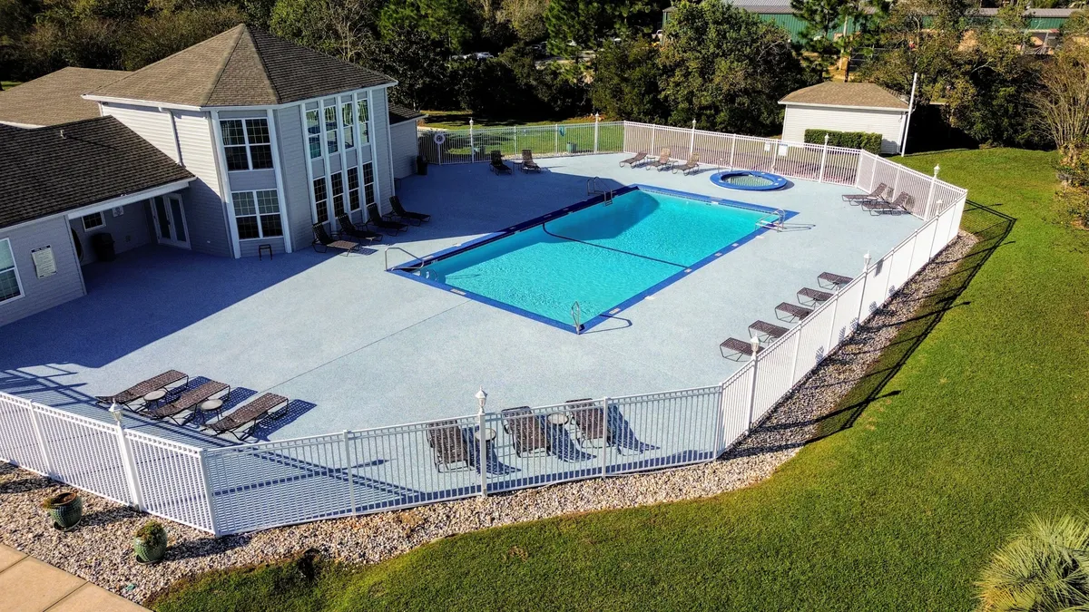 An inviting view of a sparkling outdoor swimming pool and hot tub, surrounded by lounge chairs and a clubhouse building. The scene exudes relaxation and leisure, perfect for unwinding after a day of sports or adventure.